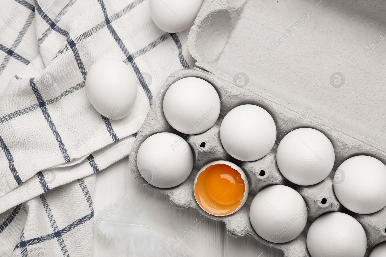 Photo of Fresh raw chicken eggs in box on white wooden table, flat lay