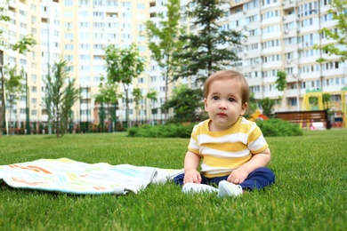 Photo of Adorable little baby sitting on green grass outdoors. Space for text