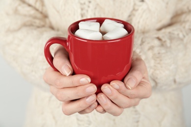 Photo of Woman in sweater holding cup of delicious marshmallow cocoa, closeup