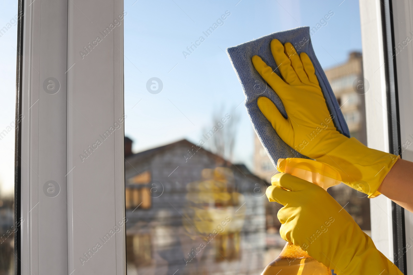 Photo of Young woman cleaning window glass with rag and detergent at home, closeup. Space for text