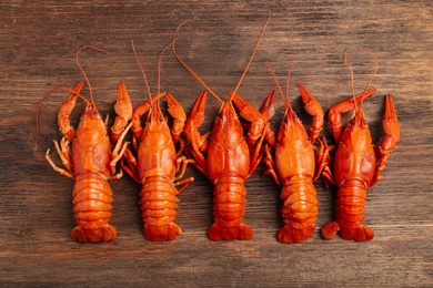 Delicious boiled crayfishes on wooden table, flat lay