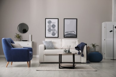 Stylish living room interior with white sofa, armchair and small coffee table