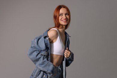 Photo of Beautiful young woman in denim jacket on gray background