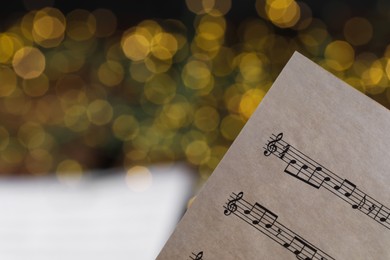 Photo of Note sheet against blurred lights, closeup with space for text. Christmas music