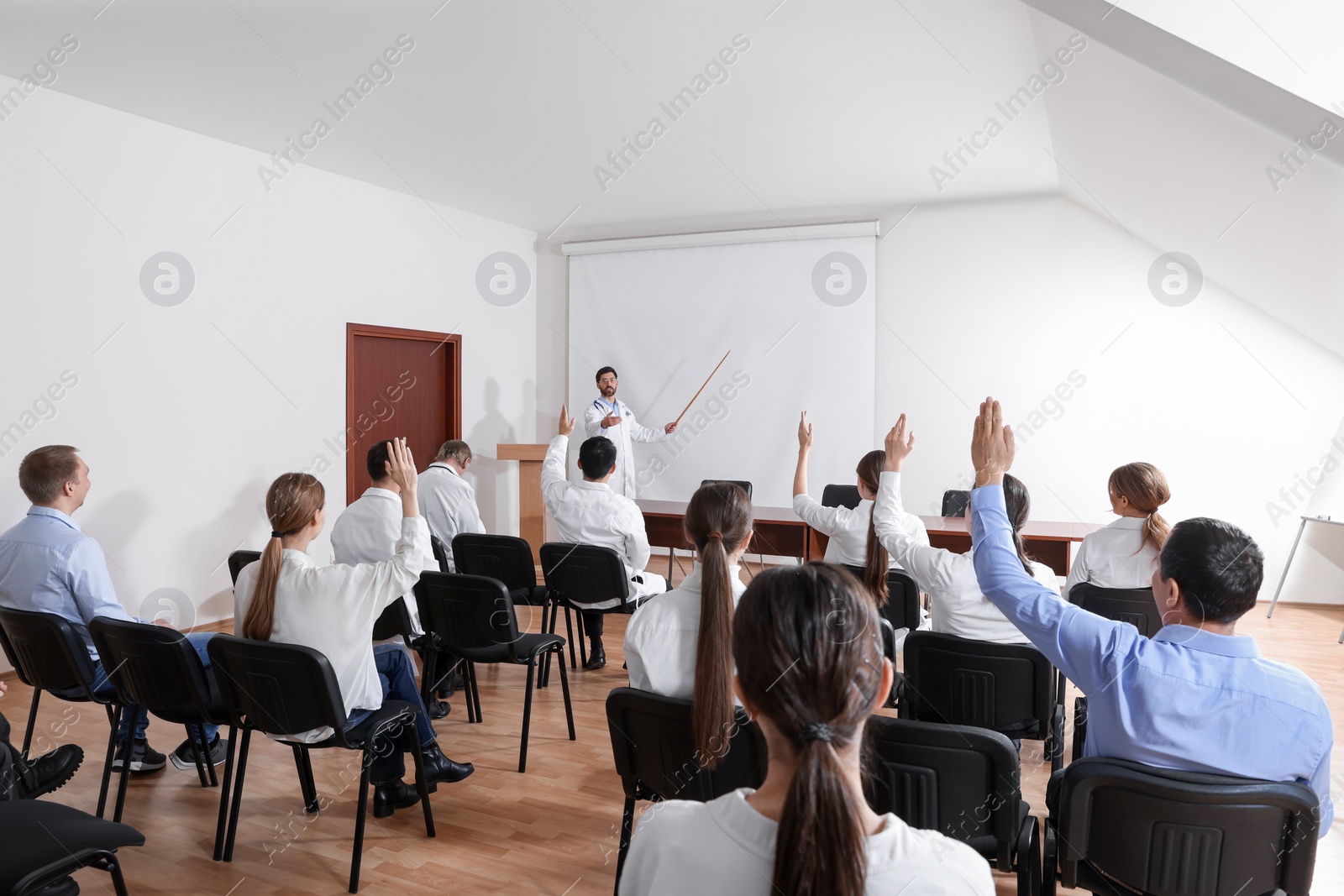 Photo of Doctor giving lecture in conference room with projection screen