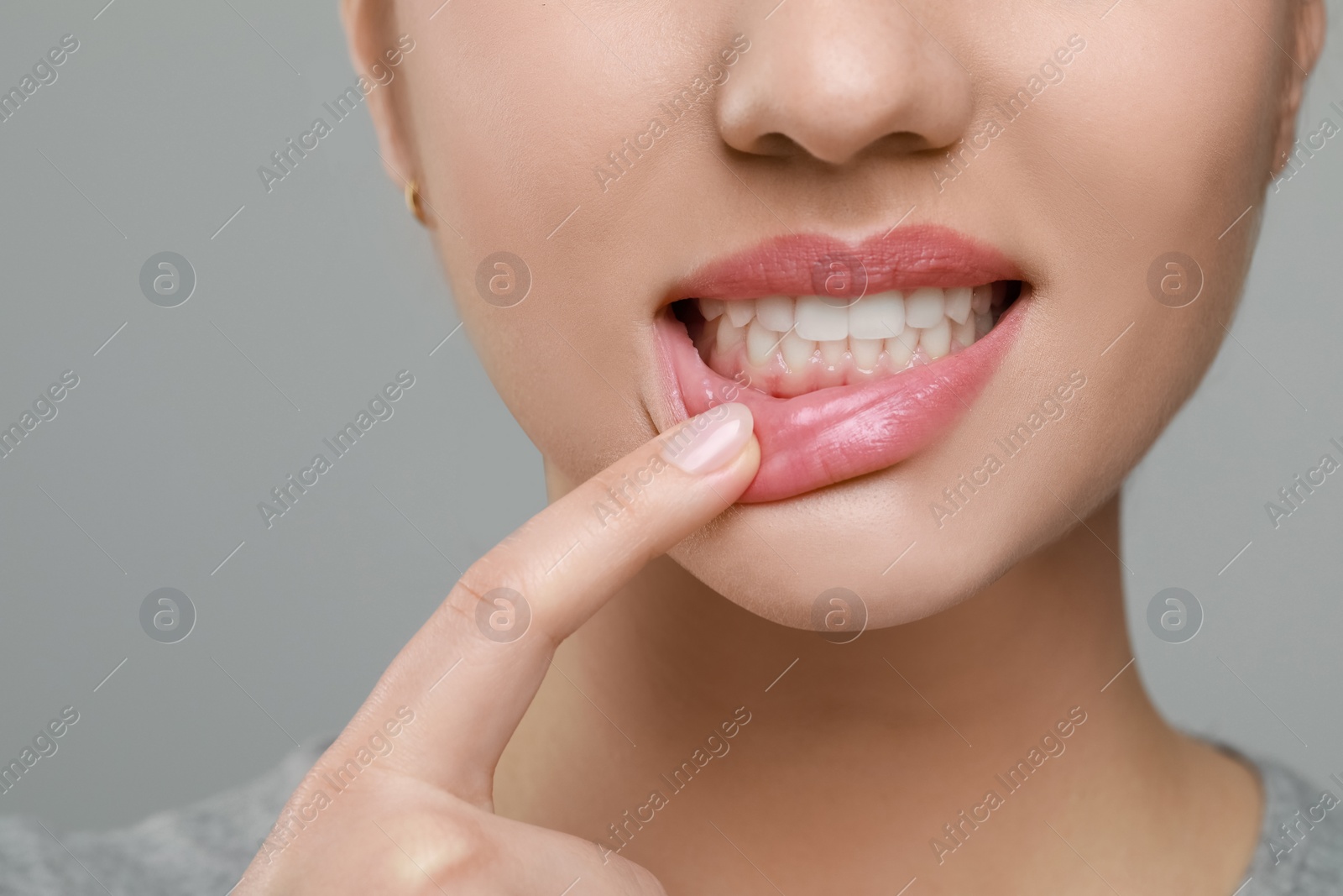 Photo of Woman showing healthy gums on grey background, closeup