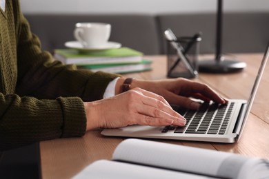 Photo of Woman with modern laptop learning at table indoors, closeup