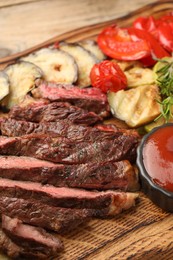 Photo of Delicious grilled beef with vegetables, tomato sauce and spices on table, closeup