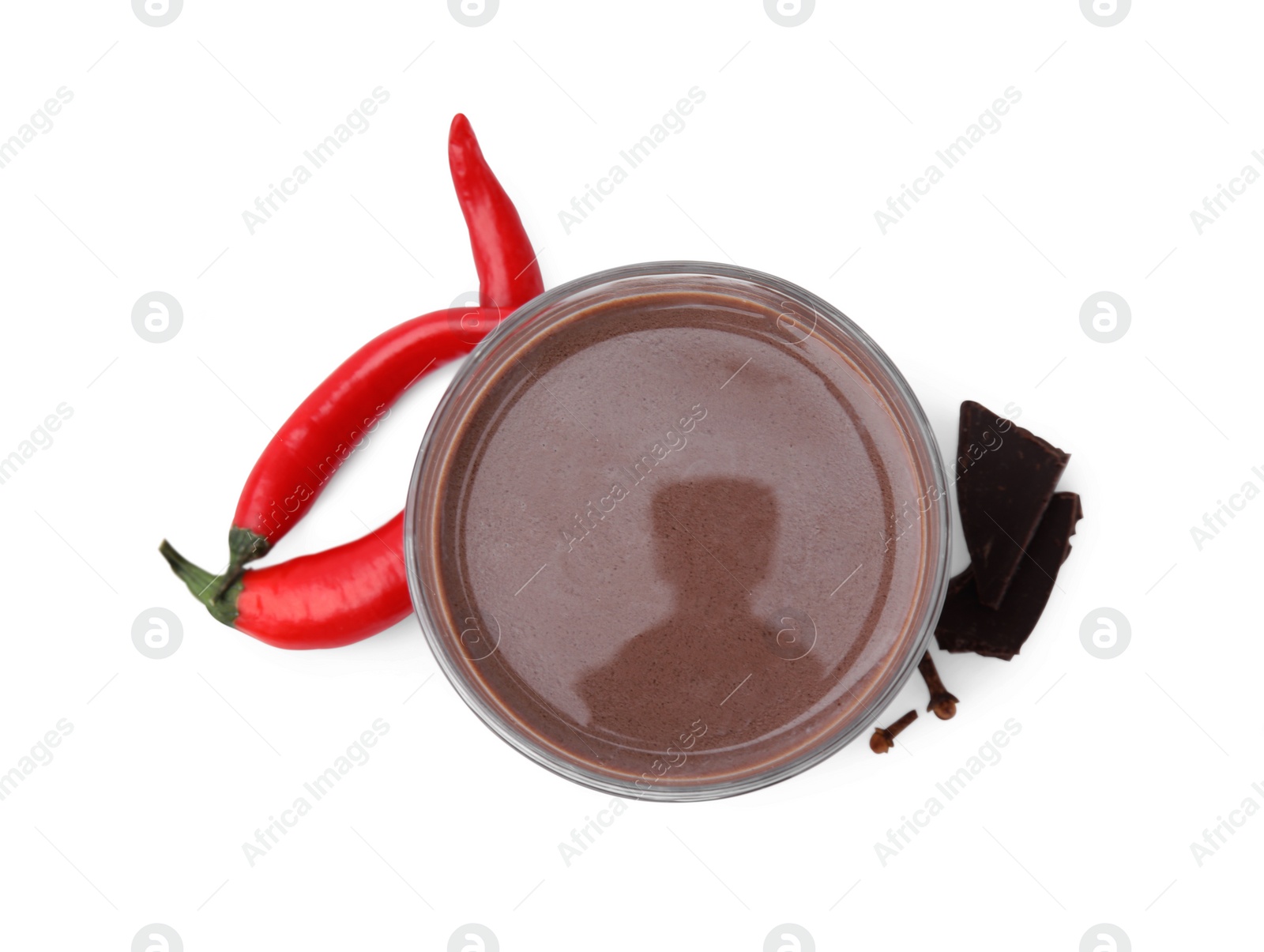 Photo of Glass of hot chocolate with chili peppers on white background, top view