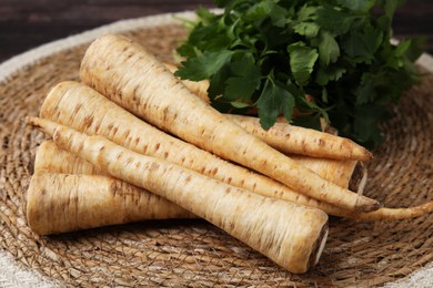 Raw parsley roots and fresh herb on wicker mat, closeup