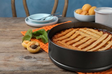 Photo of Delicious apricot pie in baking dish on wooden table