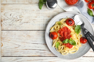 Flat lay composition with tasty pasta on white wooden table, space for text