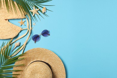Flat lay composition with bag, palm leaves and other beach accessories on light blue background. Space for text