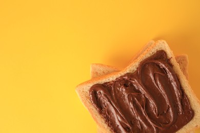 Photo of Tasty toast with chocolate paste on yellow background, top view. Space for text