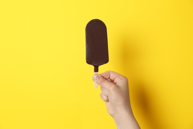 Photo of Woman holding delicious ice cream with chocolate against color background