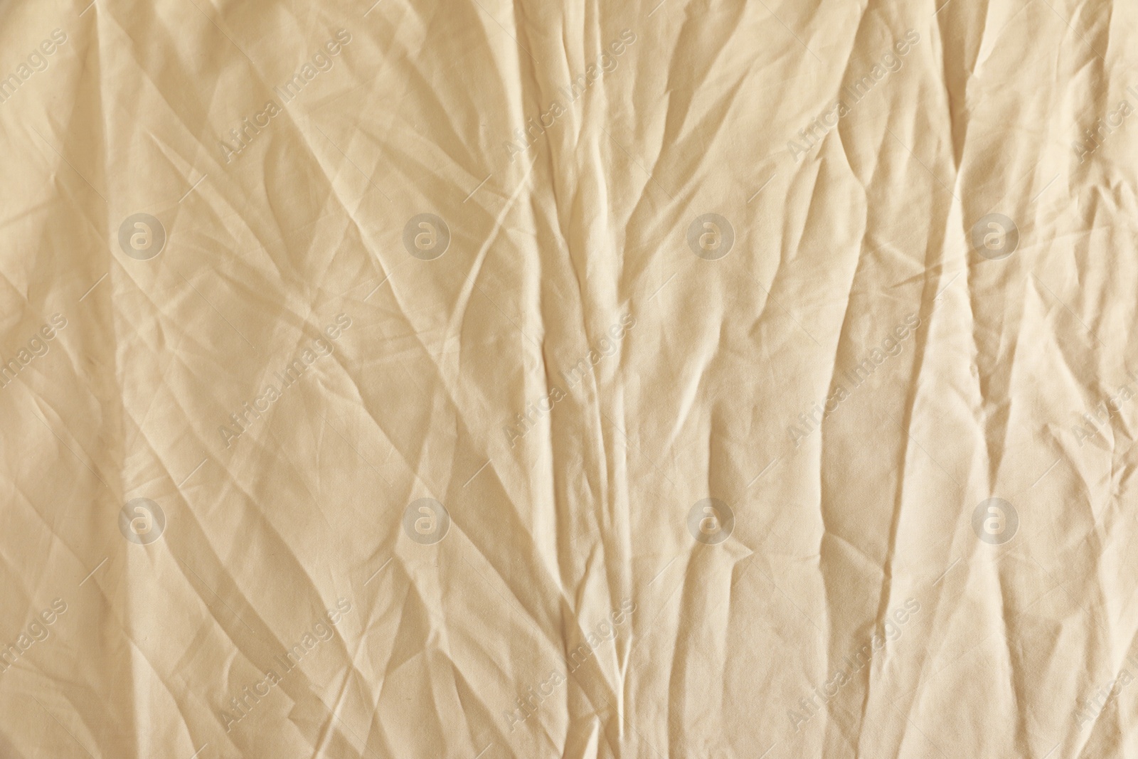 Photo of Crumpled beige fabric as background, top view