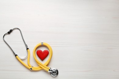 Photo of Stethoscope and red heart on white wooden table, flat lay with space for text. Cardiology concept