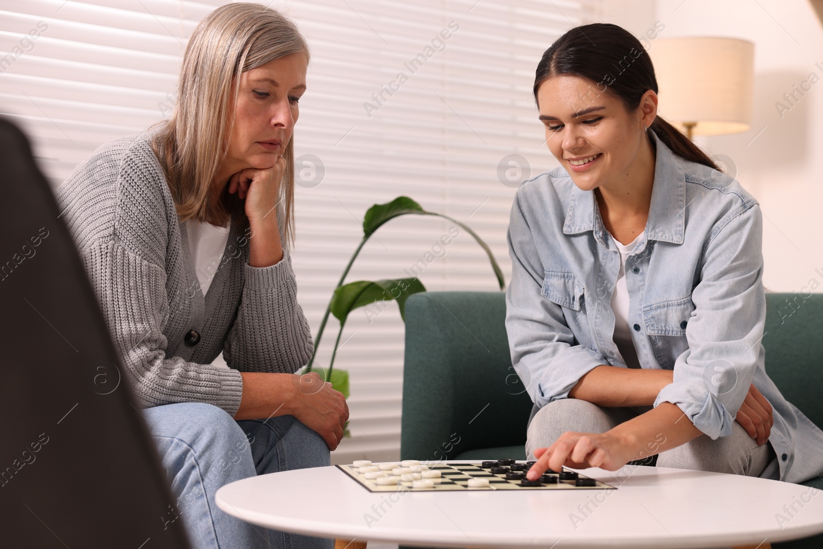 Photo of Women playing checkers at coffee table in room