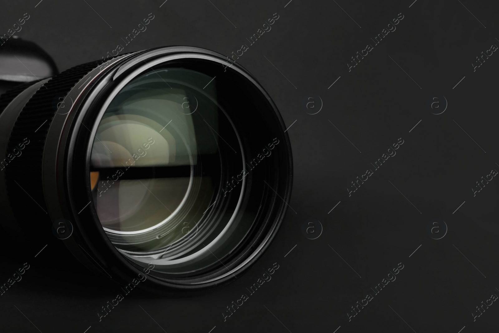 Photo of Modern camera lens on black background, closeup. Space for text