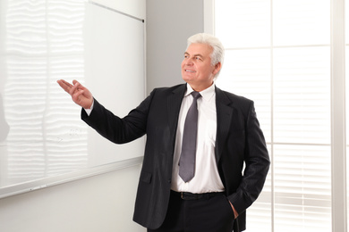 Senior business trainer near whiteboard in office