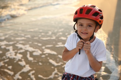 Photo of Cute little boy with bicycle on sandy beach near sea