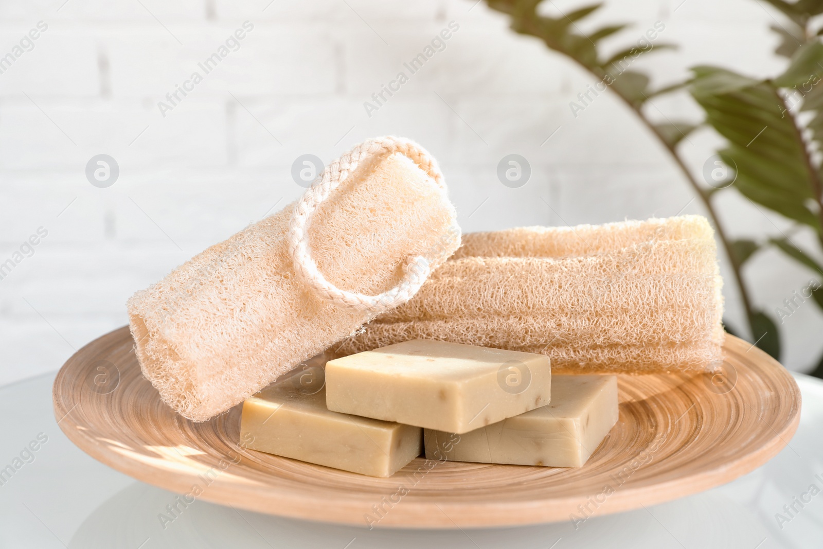 Photo of Plate with handmade soap bars and sponges on table