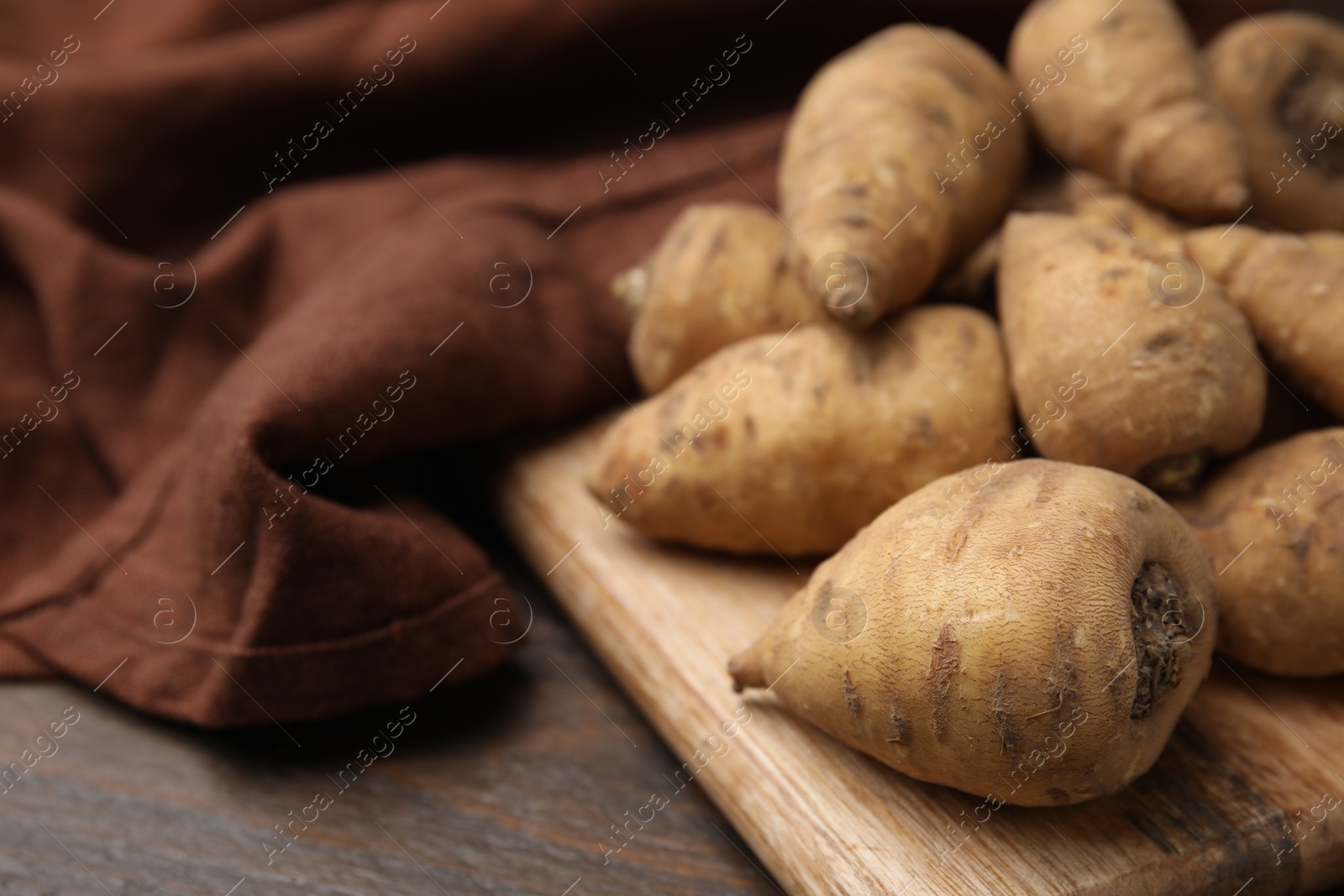 Photo of Tubers of turnip rooted chervil on wooden table, closeup. Space for text