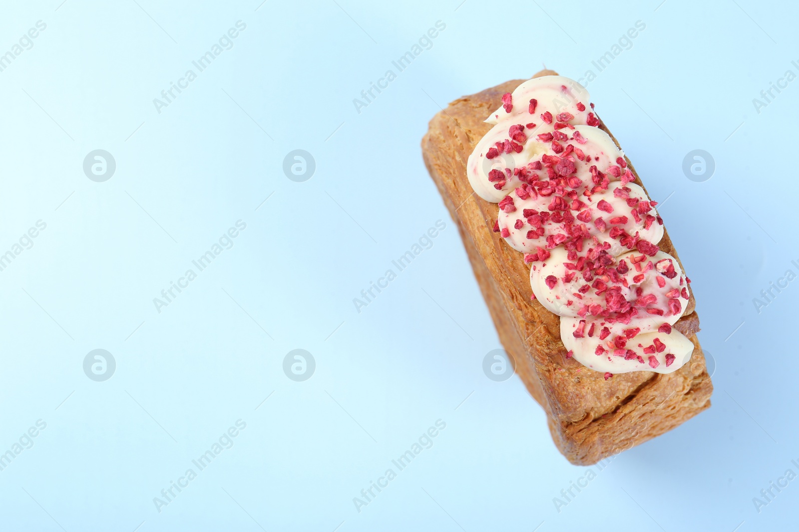 Photo of One supreme croissant with cream on light blue background, top view with space for text. Tasty puff pastry