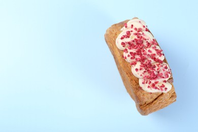 Photo of One supreme croissant with cream on light blue background, top view with space for text. Tasty puff pastry