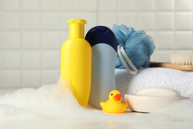 Photo of Baby cosmetic products, bath duck, brush and towel on white table