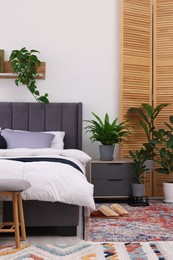 Beautiful green houseplants and bed in room. Bedroom interior