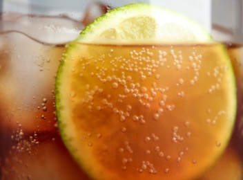 Photo of Glass of refreshing soda drink with ice cubes and lime, closeup