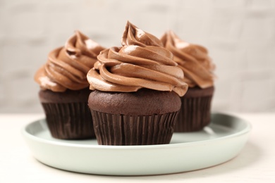 Photo of Delicious fresh chocolate cupcakes with cream on white table, closeup