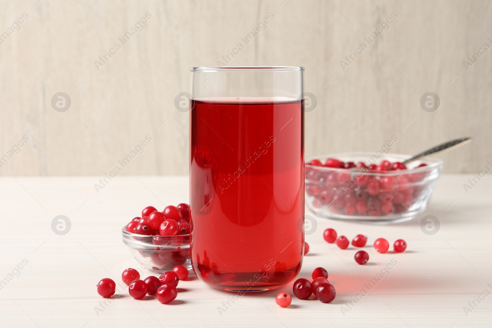 Photo of Tasty cranberry juice in glass and fresh berries on white wooden table