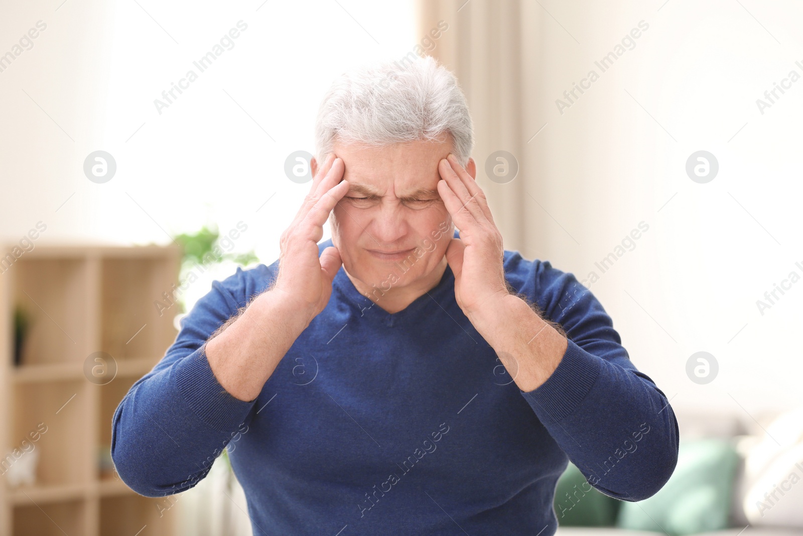 Photo of Mature man suffering from headache at home