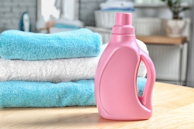 Stack of clean towels and bottle with detergent on table