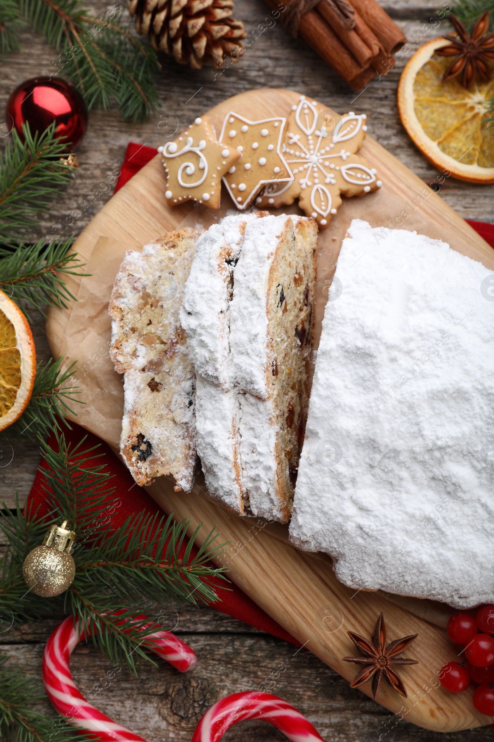 Photo of Traditional Christmas Stollen with icing sugar on wooden table, flat lay