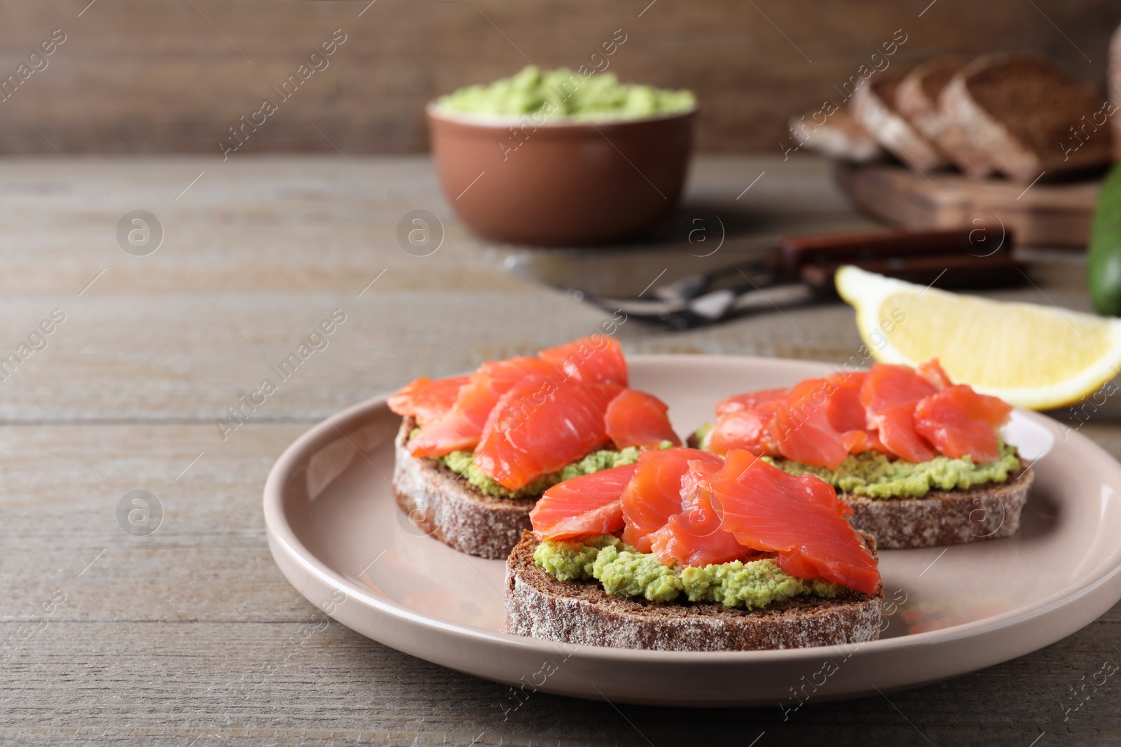 Photo of Delicious sandwiches with salmon and avocado on grey wooden table. Space for text