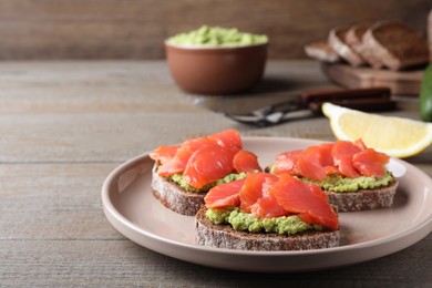 Photo of Delicious sandwiches with salmon and avocado on grey wooden table. Space for text