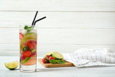 Delicious refreshing drink with strawberry and lime on white wooden table. Space for text