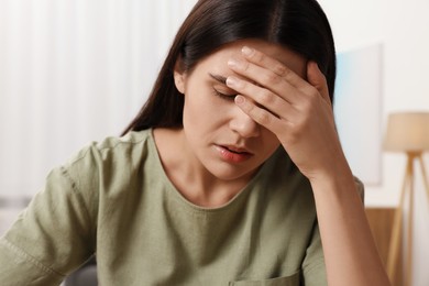 Sad woman suffering from headache at home