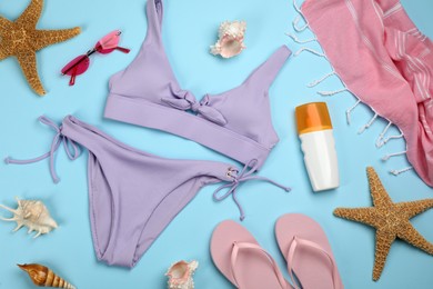 Photo of Flat lay composition with swimsuit and beach accessories on light blue background