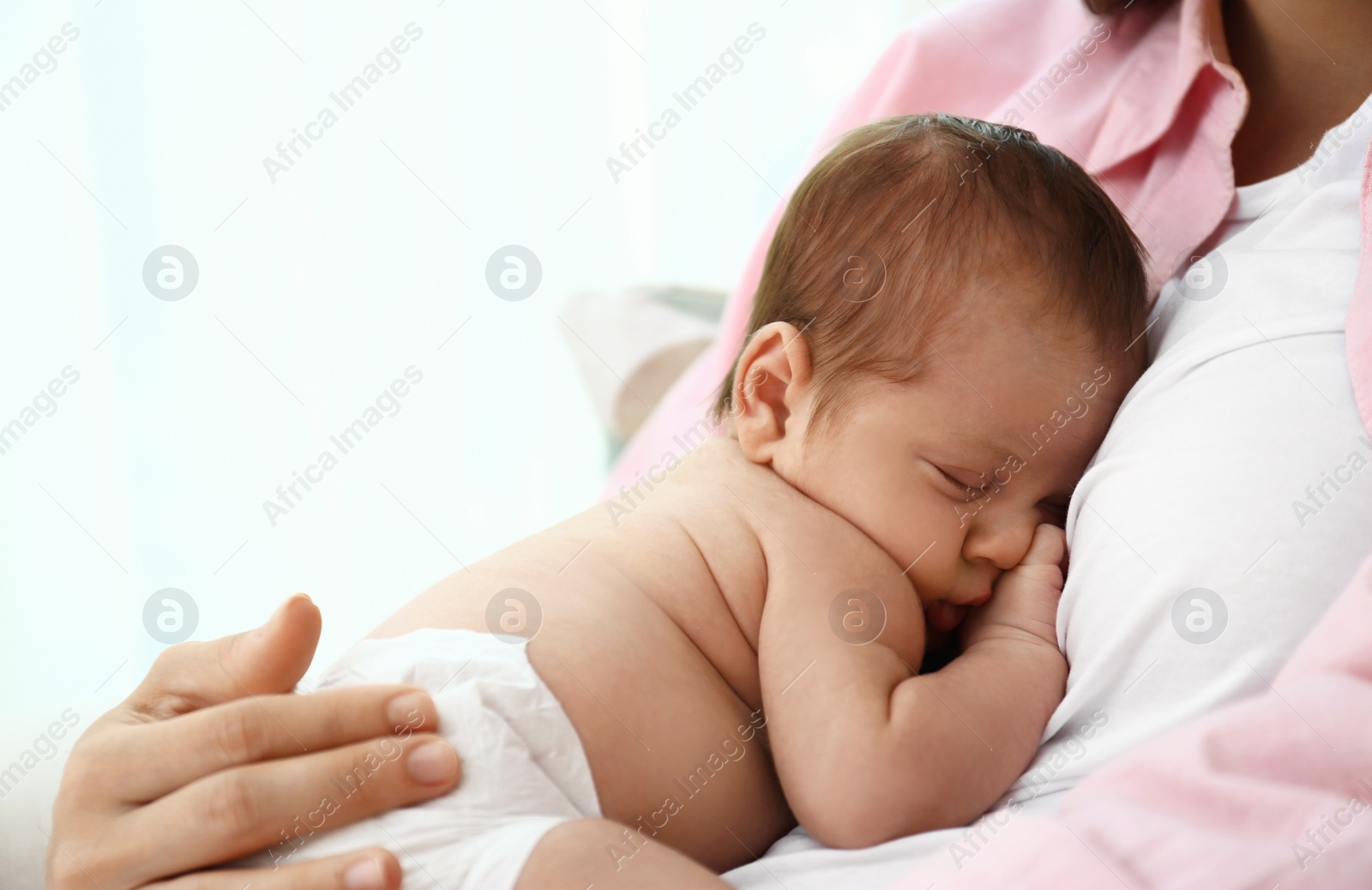 Photo of Young mother with her little baby on light background