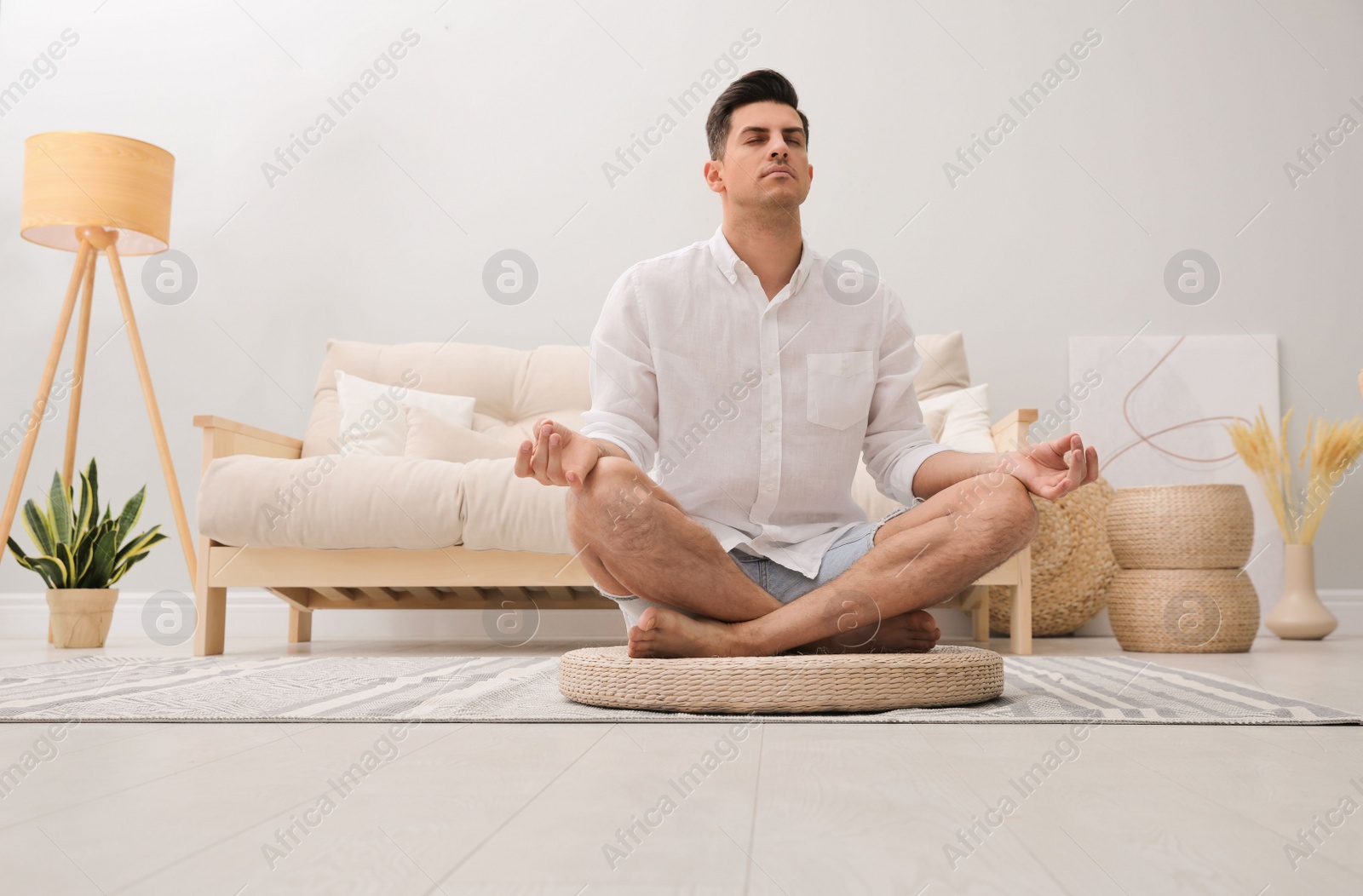 Photo of Man meditating on wicker mat at home