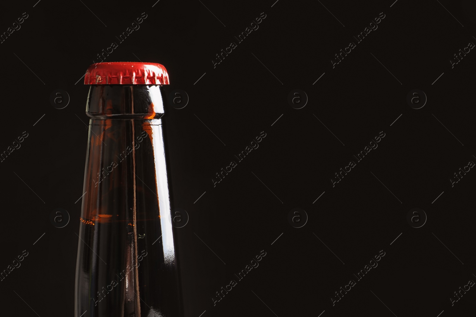 Photo of Bottle of tasty cold beer on black background, closeup