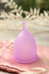 Photo of Menstrual cup and bag on table indoors, closeup