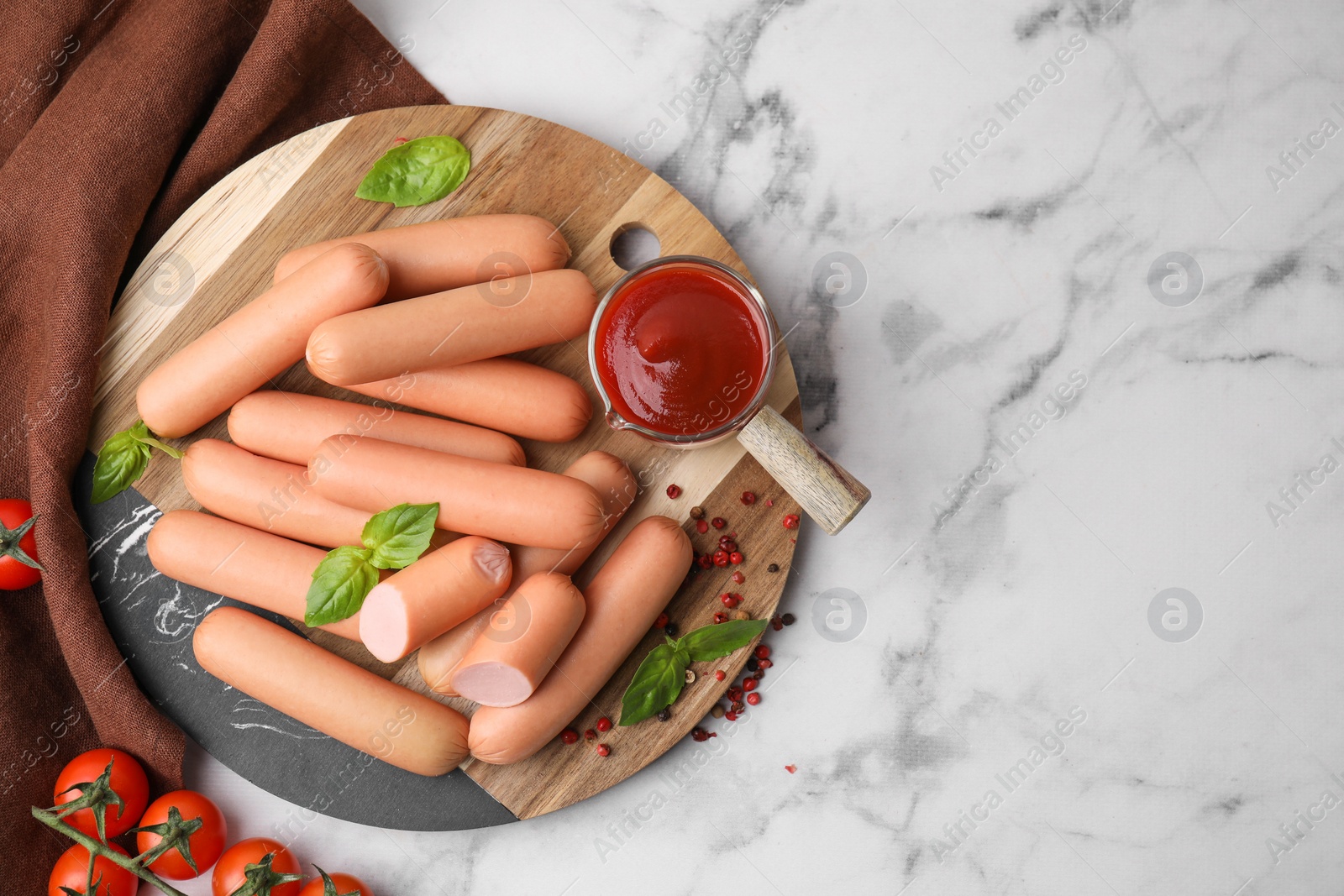 Photo of Delicious boiled sausages with spices, sauce and tomatoes on white marble table, flat lay. Space for text