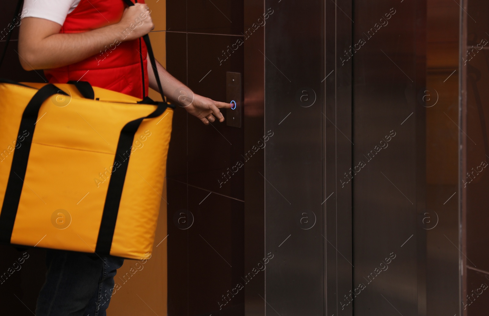 Photo of Male courier with thermo bag pushing elevator button, closeup. Food delivery service