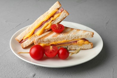 Photo of Tasty sandwiches with ham, melted cheese and tomatoes on grey textured table, closeup