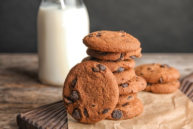 Stack of tasty chocolate chip cookies on wooden board